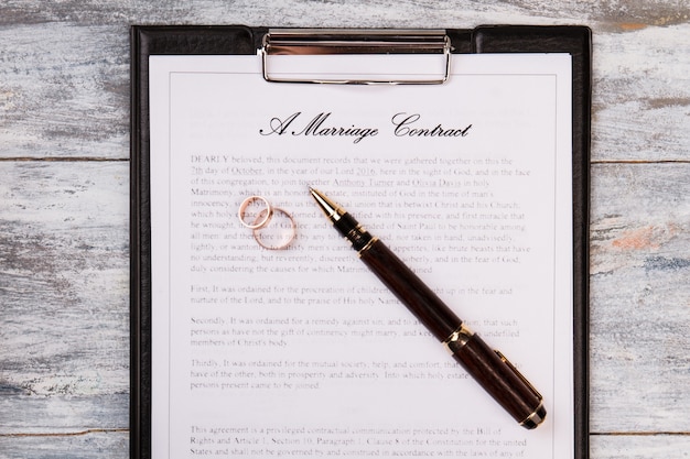 Marriage contract with pen and wedding rings.