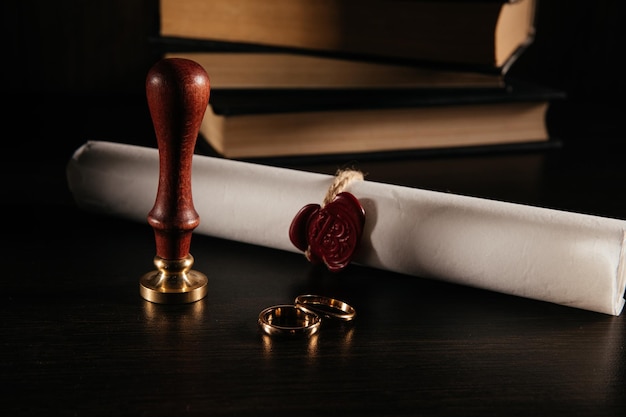 Contratto di matrimonio con sigillo e anelli d'oro in un primo piano dell'aula di tribunale concetto di divorzio