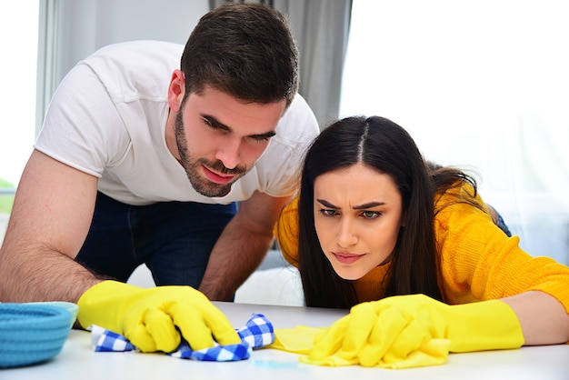 Marriage life, couples, cleaning, household works and duties concept. Young man and woman cleaning and wiping the house together.e