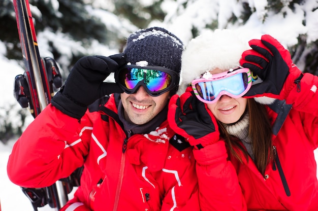 Married couple in bright jackets preparing to ski together in the winter forest.