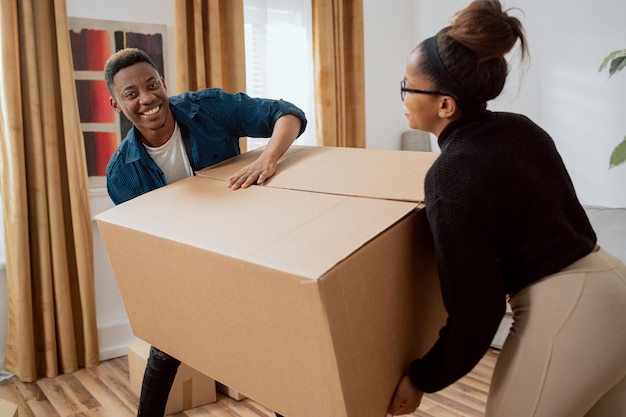 Married couple carry heavy boxes while moving to a new apartment