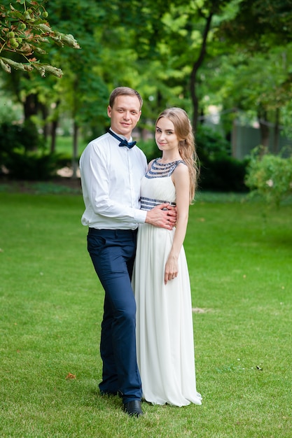 A married couple is walking and hugging in the park.