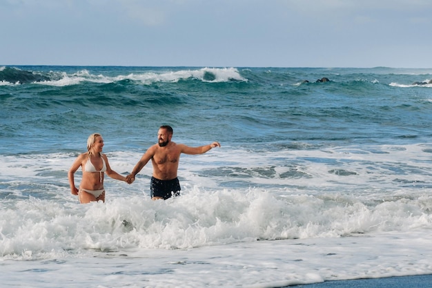 A married couple swims in the sea on the waves holding hands The concept of a romantic trip