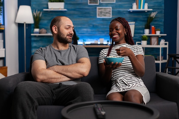 Married interracial couple laughing and chatting in living room