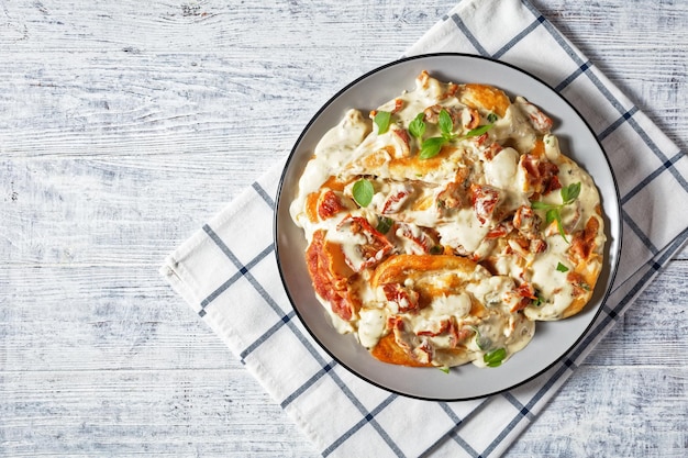 Marry Me Chicken, kipfilet gebakken in roomsaus met zongedroogde tomaten, tijm, rode pepervlokken, basilicum en krokant gebakken bacon geserveerd op een bord, plat gelegd, Amerikaanse keuken