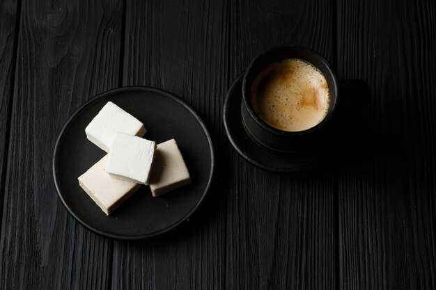 Marshmallow in un piatto nero sul tavolo di legno nero