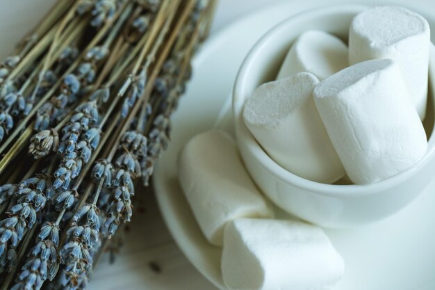 Photo marshmallow in a cup and lavender on a white wooden background