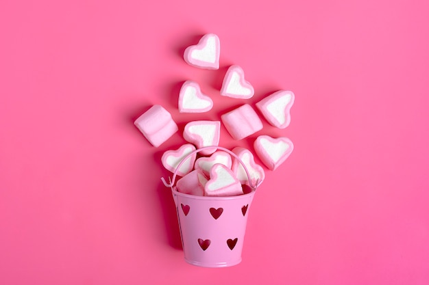 Marshmallow hartvormige gemorst uit emmer op roze achtergrond happy valentine's day