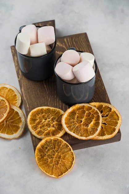 Marshmallow met koffie in kopje met gedroogde gesneden sinaasappel op snijhouten plaat