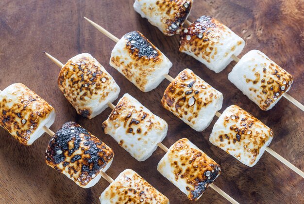 Marshmallow skewers on the wooden surface