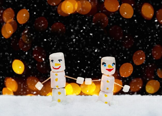 Marshmallow snowmen holding hands. Holiday concept. Christmas background with sweets.