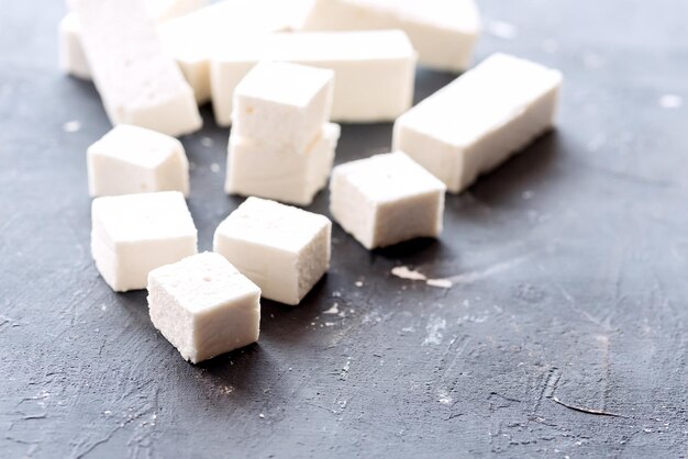 Marshmallow sticks and cubes lying on background Copy space on the right