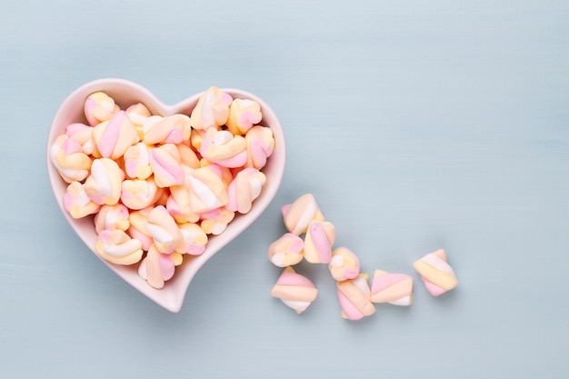 Marshmallows on blue background with copyspace. Flat lay or top view. Background or texture of colorful mini marshmallows.