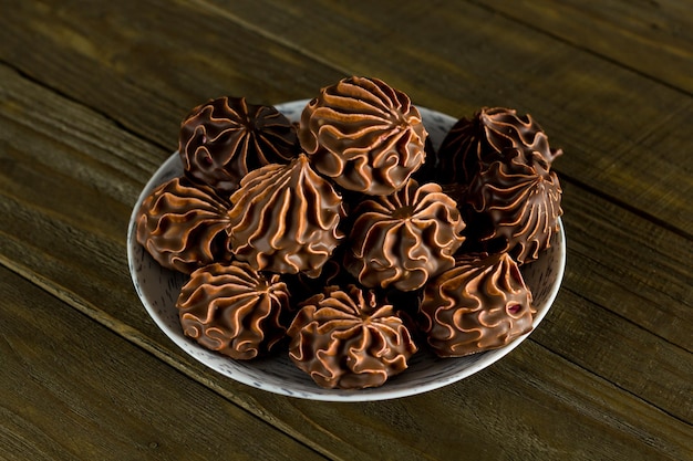 Marshmallows in chocolate on a wooden table side view\
closeup