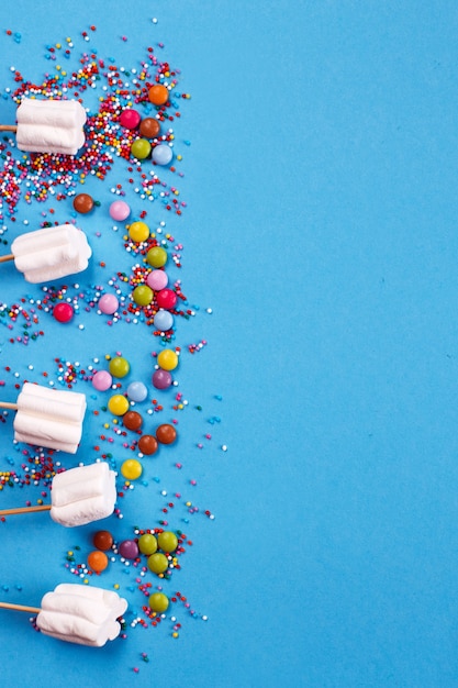 Marshmallows composition with sprinkles on a blue background