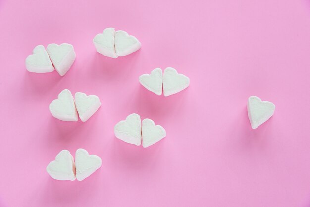 Marshmallows in heart shapes for Valentines day over pink paper background