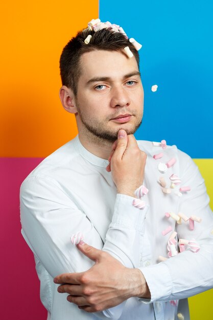 Photo marshmallows sprinkle on the man’s head. bright man portrait with sweets on his hair. sweets on the guy's face