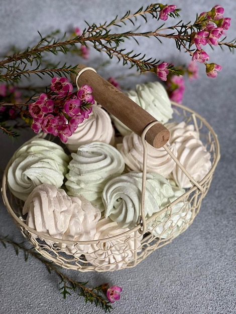 marshmallows sprinkled with powdered sugar in a metal light basket on a background of flowers