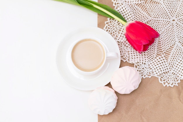marshmallows, tea or coffee with milk and a tulip flower. on a light surface. romantic spring morning. delicate breakfast, breakfast in bed. for the beloved. surprise.