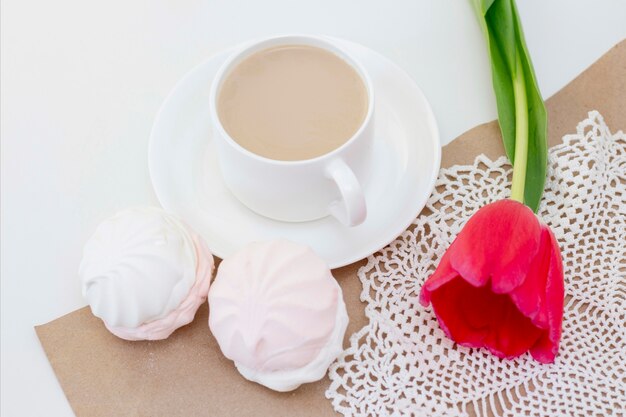 Marshmallows, tea or coffee with milk and a tulip flower. on a light surface Romantic spring morning. delicate breakfast, breakfast in bed. for the beloved. Surprise.