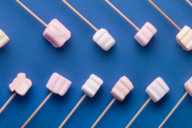 Marshmallows on wooden sticks, over blue background, marshmallow mock-up