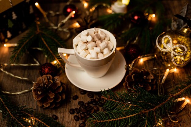 Marsmeloen in een witte beker op een tafel met kerstverlichting Kerstboom