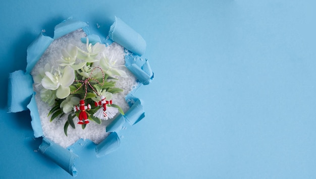 Martenitsa Martisor met bloemen in de sneeuw op een blauwe achtergrond