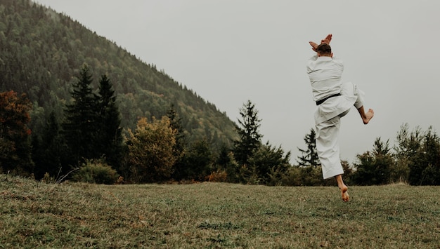 Martial art of karate a man in a kimono with black belt trains\
on the mountainfree space