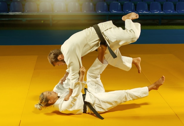 Martial arts. Sparing Portners. Sport man and woman in white kimono train judo throws and captures in the sports hall