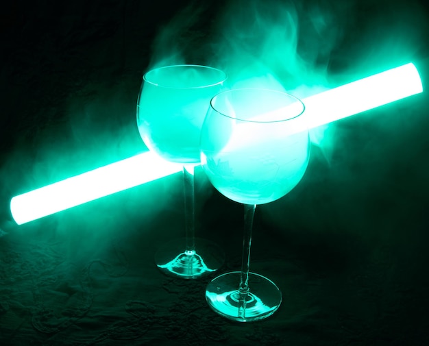 Foto cocktail martini coperto di fumo in una luce verde neon. il tubo illuminante è luminoso