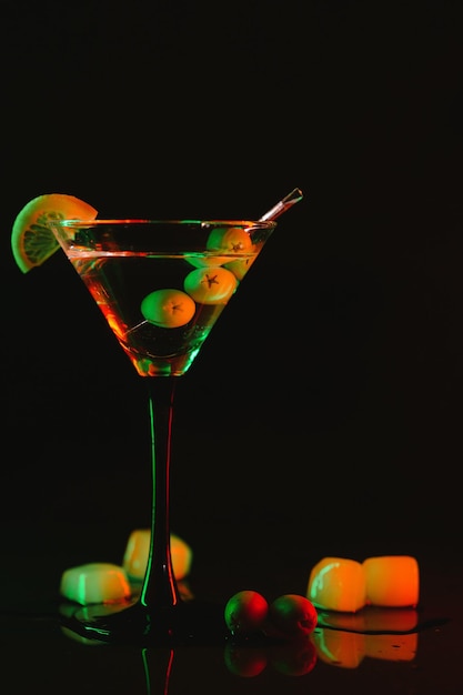 Martini glass and olives on a black background with neon lights