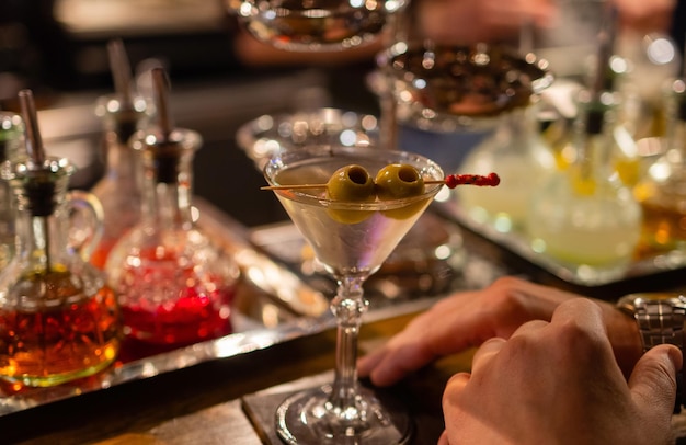 Martini with green olives on a table in bar