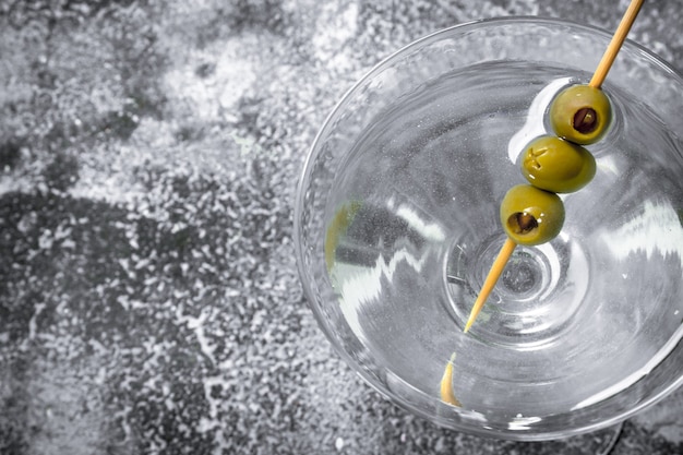 Martini with olives on a rustic table.