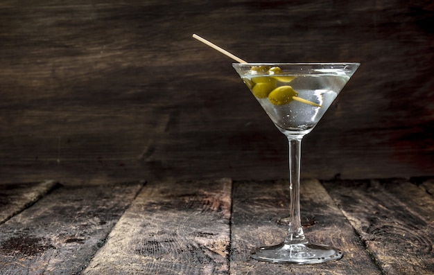 Martini with olives on a wooden table.