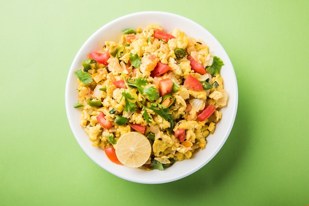 Masala Anda Bhurji or Spicy Indian scrambled eggs, Popular street food in Mumbai. Served in white crockery, isolated over moody background. selective focus