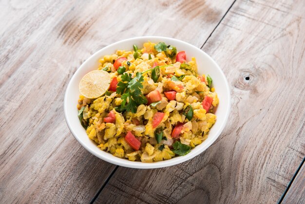 Masala Anda Bhurji or Spicy Indian scrambled eggs, Popular street food in Mumbai. Served in white crockery, isolated over moody background. selective focus