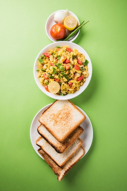 Masala Anda Bhurji or Spicy Indian scrambled eggs with roasted bread or Bun or Pav, Popular street food in Mumbai. Served in white crockery over moody background. selective focus