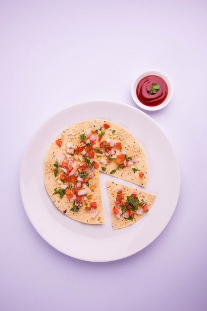 Masala papad is een Indiaas vegetarisch krokant gerecht of voorgerecht dat heel gemakkelijk te maken is. Geserveerd met tomatenketchup over humeurige achtergrond. Selectieve focus