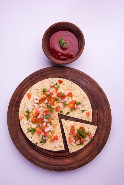 Masala papad는 매우 쉽게 만들 수 있는 인도 채식 바삭한 음식 또는 전채입니다. 변덕스러운 배경 위에 토마토 케첩과 함께 제공됩니다. 선택적 초점