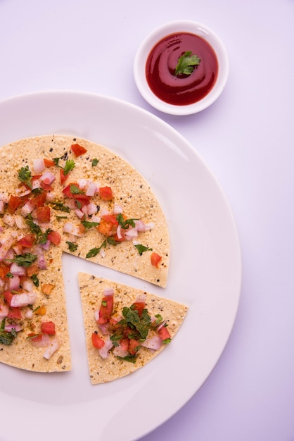 Masala papad는 매우 쉽게 만들 수 있는 인도 채식 바삭한 음식 또는 전채입니다. 변덕스러운 배경 위에 토마토 케첩과 함께 제공됩니다. 선택적 초점