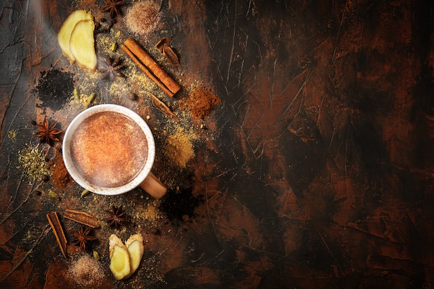 Tè masala con cannella e anice su un tavolo di argilla. una tazza di tè masala con spezie su uno sfondo di cemento. vista dall'alto.