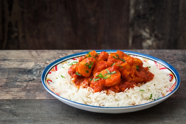 Masala van kippentikka met basmati rijst op houten lijst