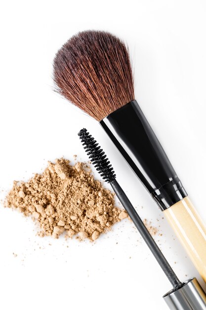 Mascara, beige powder for face and makeup brush on white background