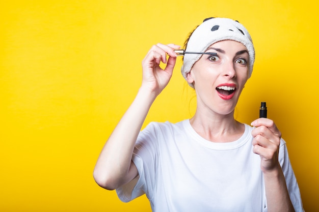 Mascara. Vrolijke jonge vrouw in een wit T-shirt doet make-up