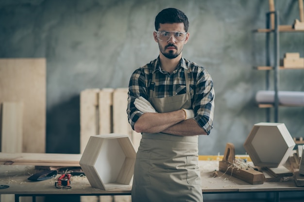 Masculine confident workman builder stand in house home garage cross hands ready repair restor all furniture workshop wear checkered plaid shirt