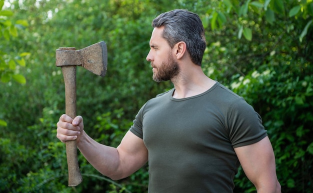 Photo masculine guy in profile with axe outdoor photo of masculine guy with axe