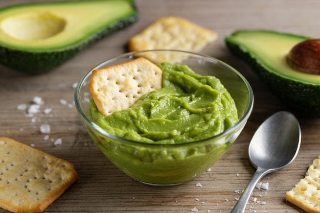 Mashed avocado guacamole sauce in bowl with crackers