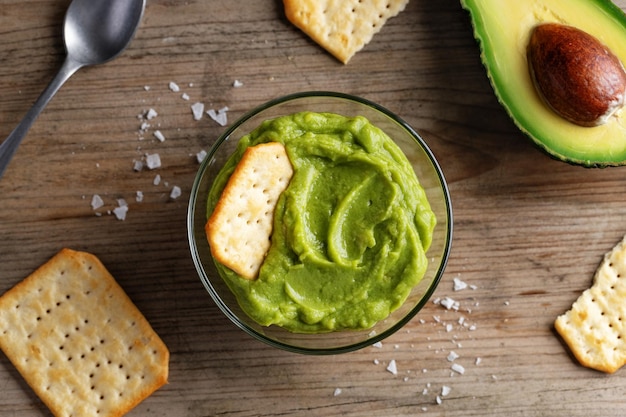 Mashed avocado guacamole sauce in bowl with crackers