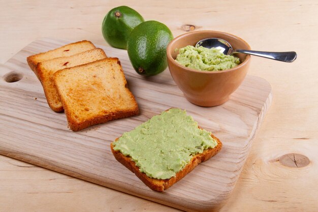 Foto tostini di avocado in purè su sfondo d'acqua beige chiaro concetto di alimentazione sana e cibo vegetariano