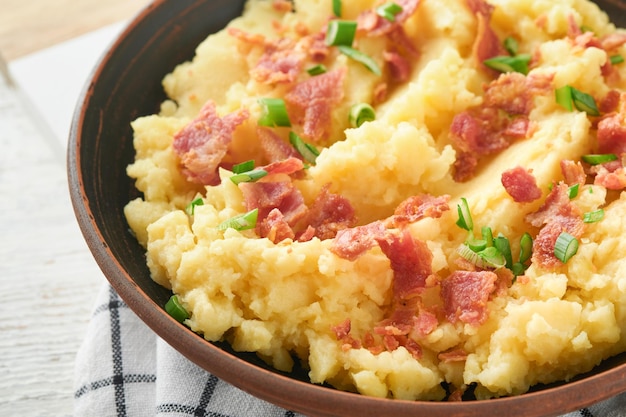 Mashed boiled potatoes Bacon mashed potatoes with green onion pepper and cheddar cheese in bowl on light old wooden backgrounds Delicious creamy mashed potatoes Top view